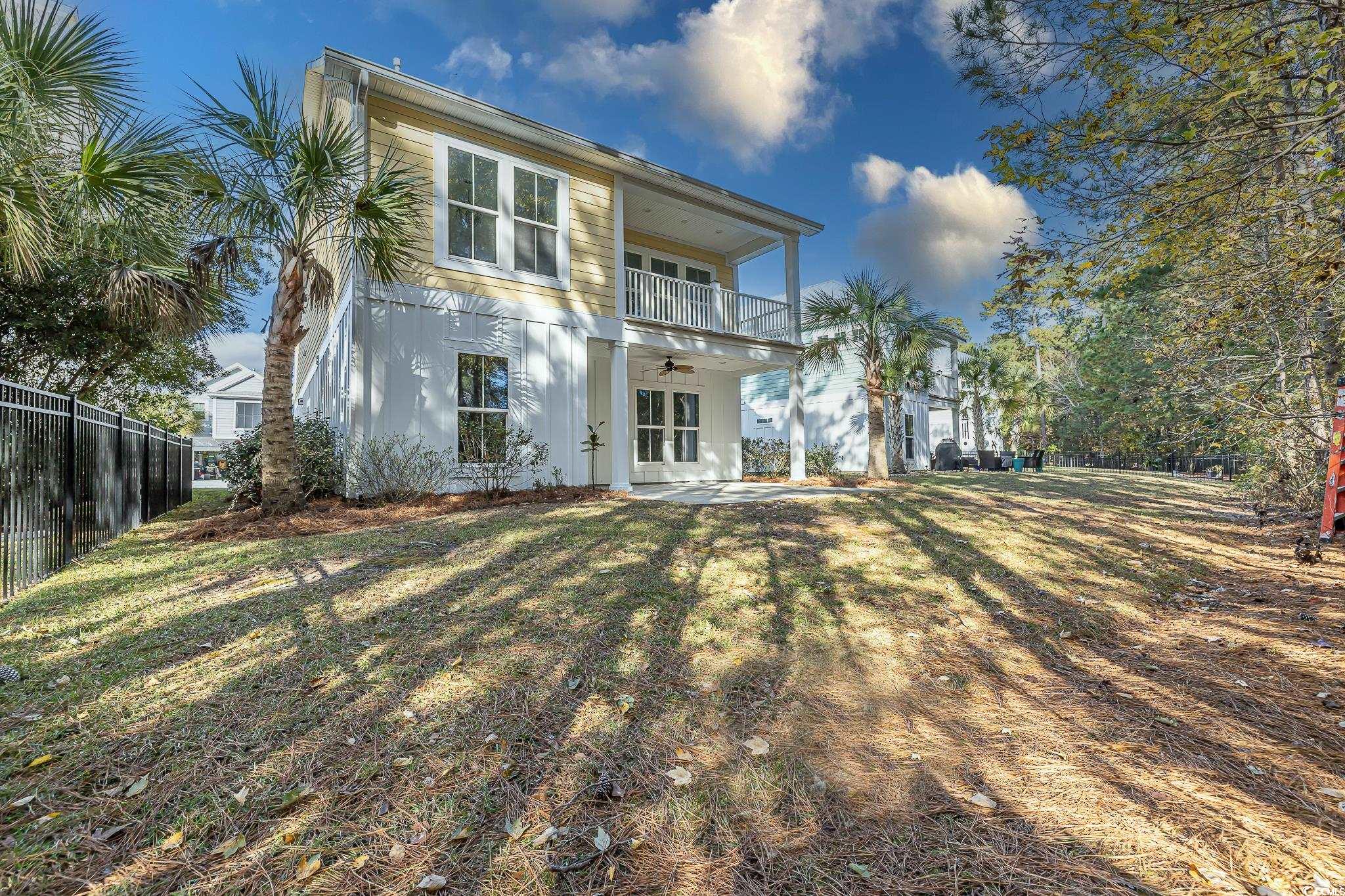 Back of house featuring ceiling fan, a balcony, a