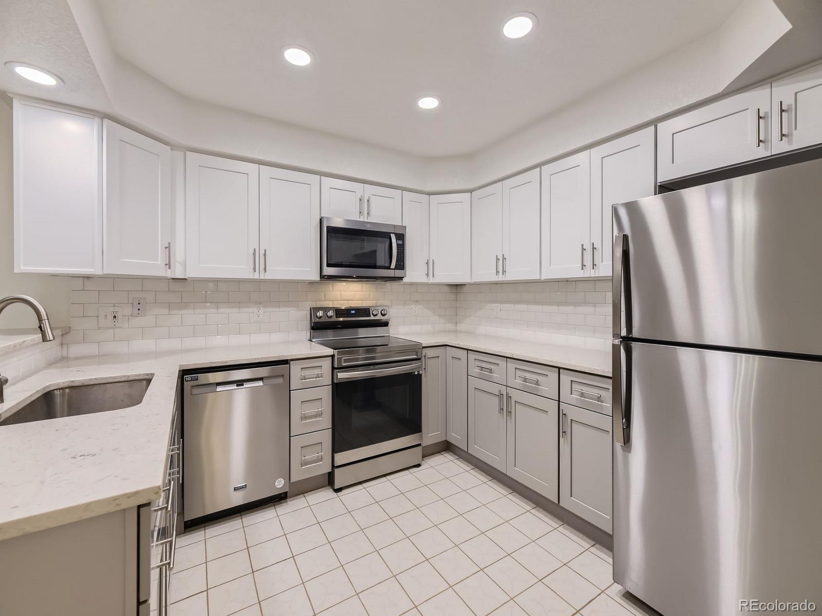 a kitchen with a refrigerator sink and white cabinets