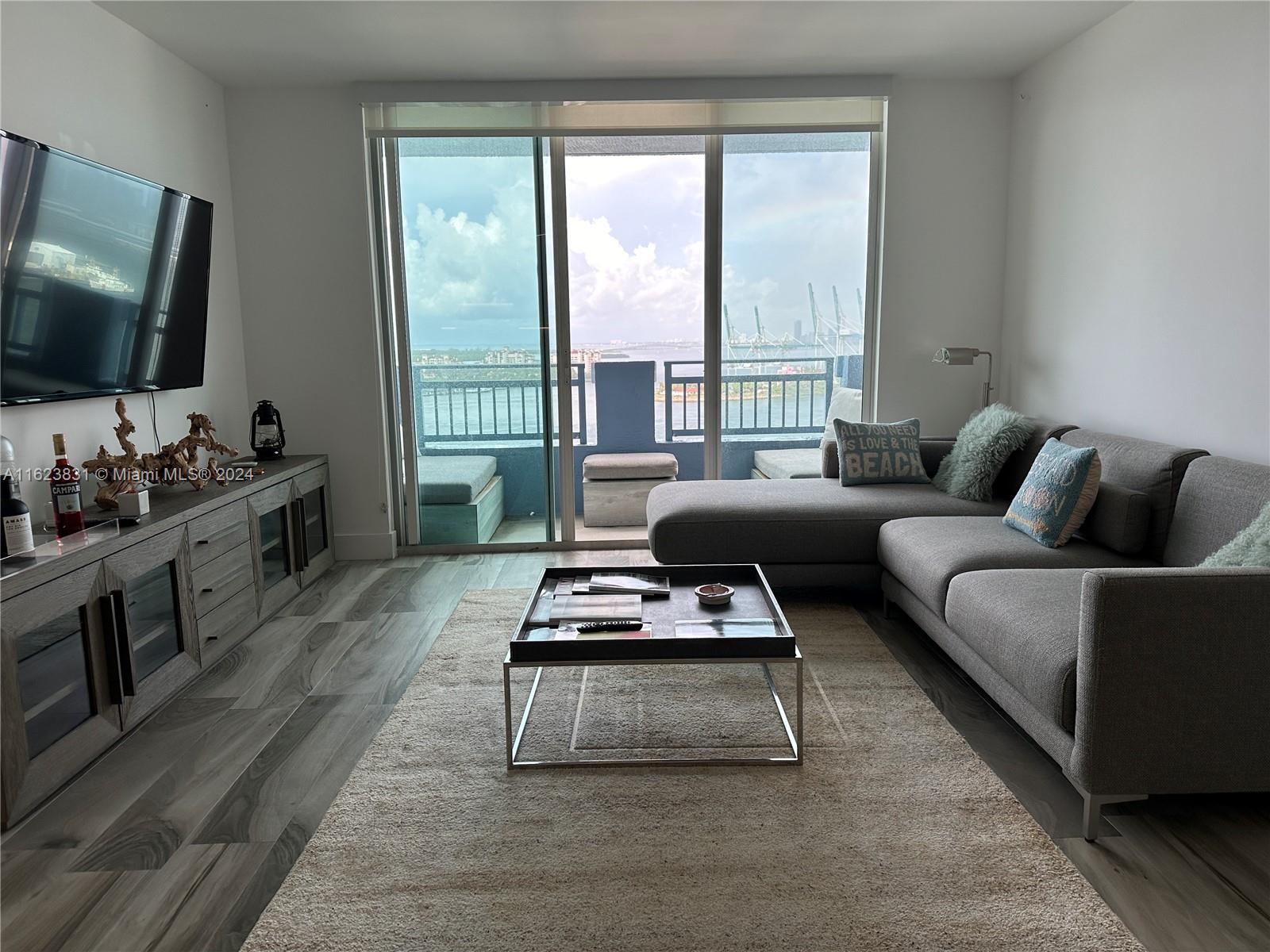 a living room with furniture flat screen tv and a large window