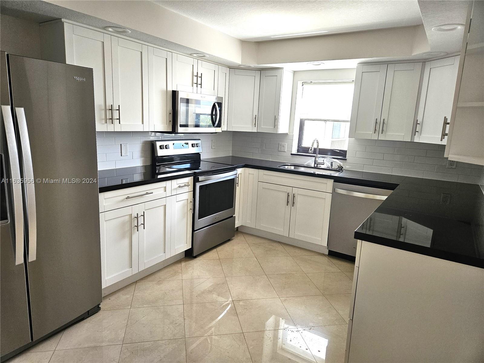 a kitchen with stainless steel appliances granite countertop a refrigerator sink and stove