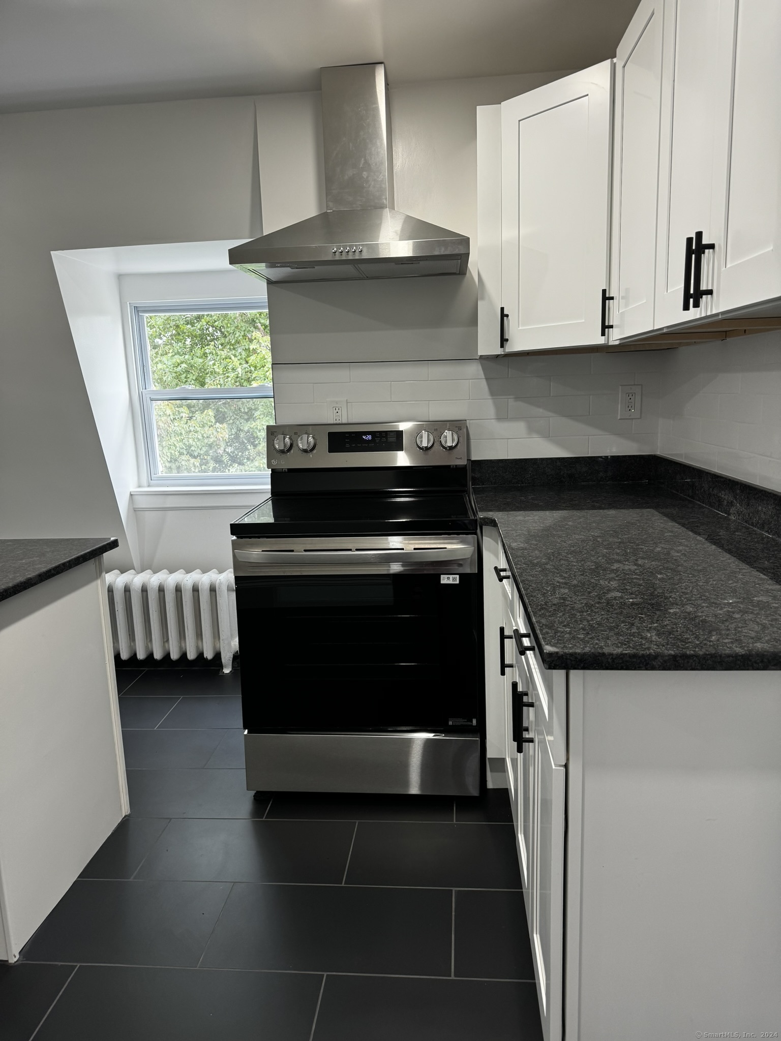 a kitchen with granite countertop a stove and a white cabinet