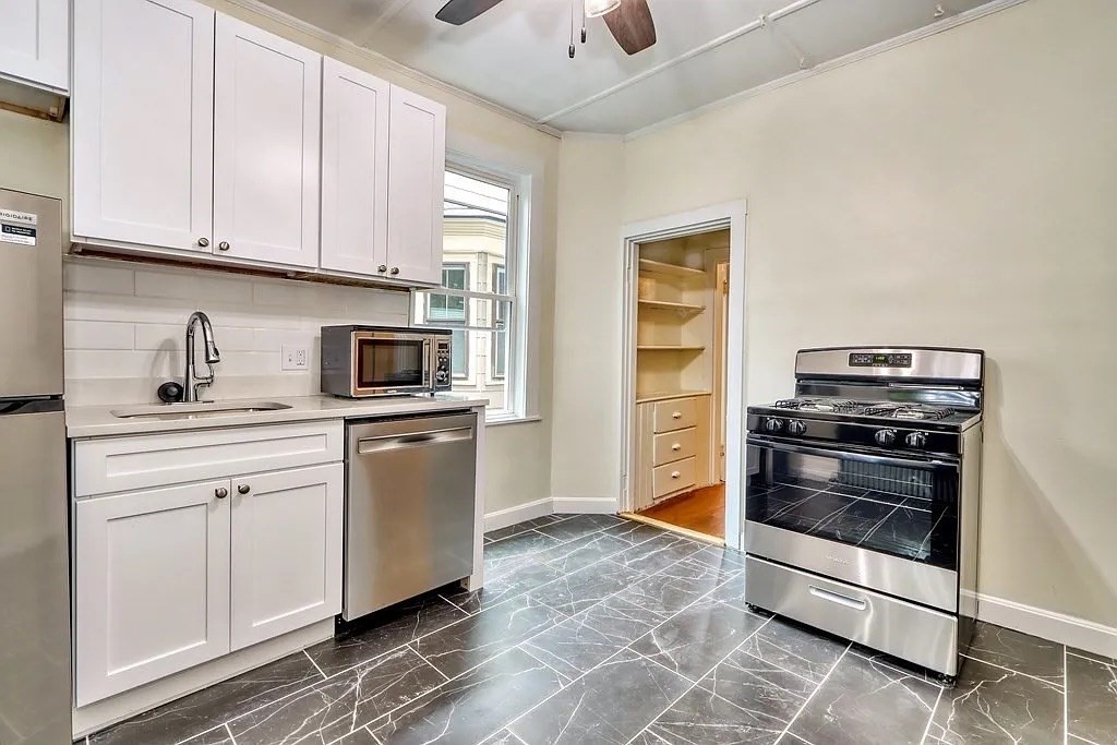 a kitchen with white cabinets and appliances