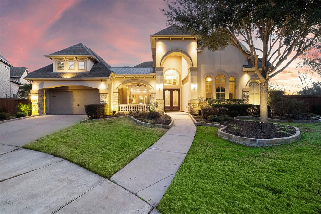 Two-story house with landscaped lawn and prominent arched entryway.