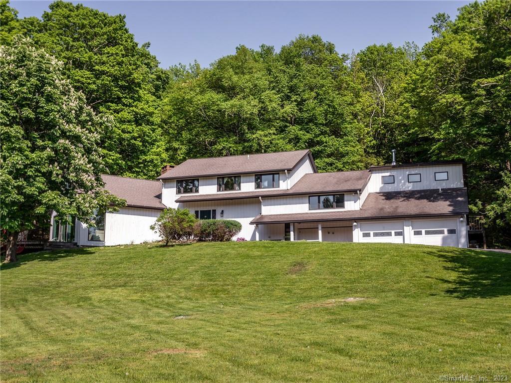 a view of a house with a big yard and large trees