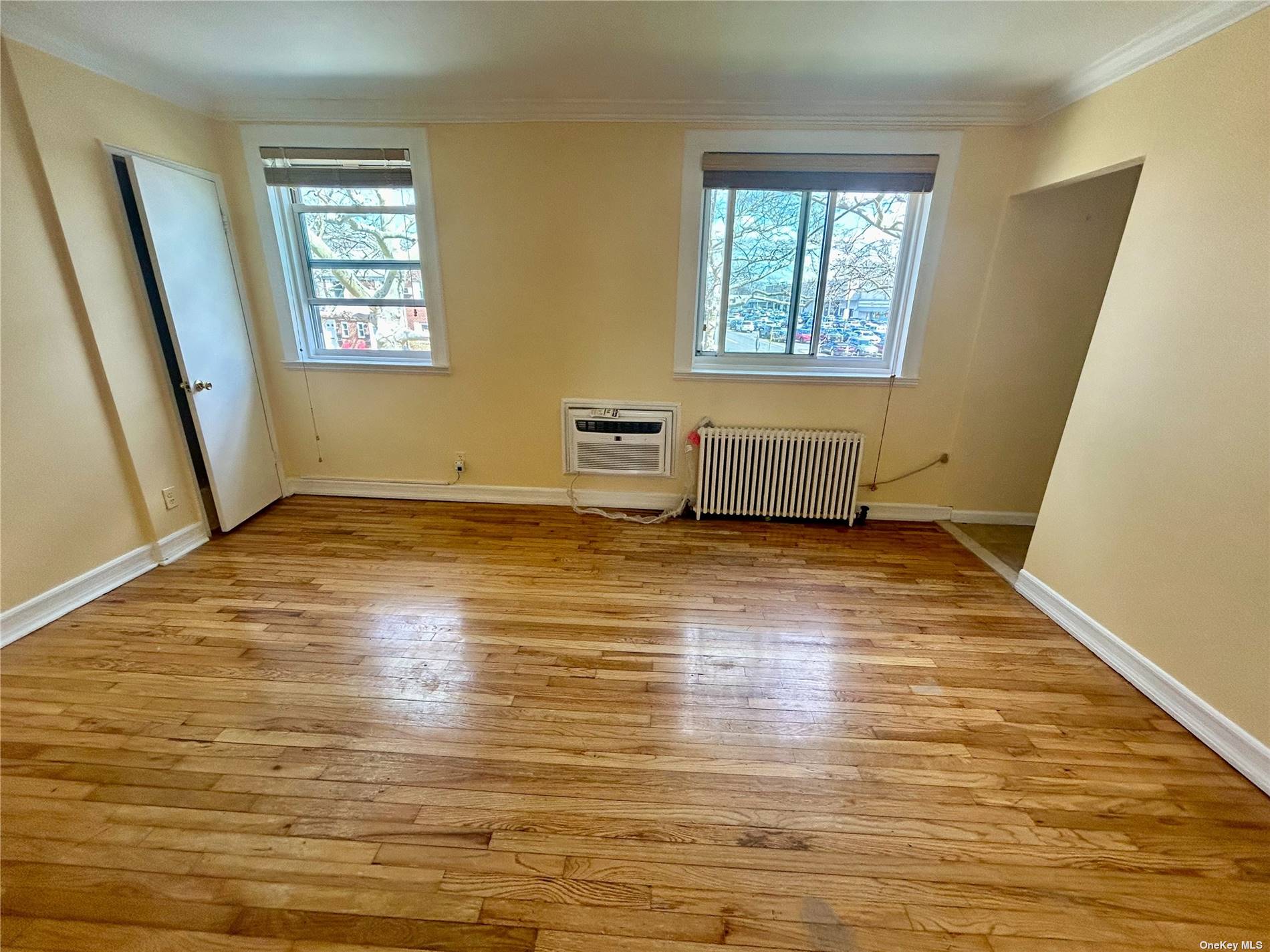 a view of an empty room with wooden floor and a window