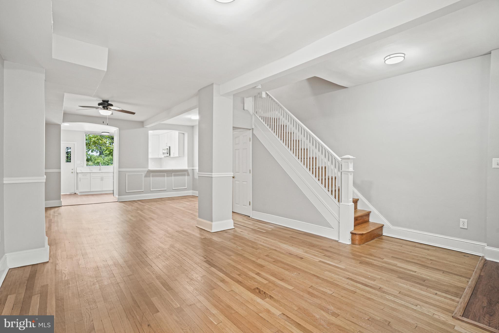 a view of an empty room with wooden floor and stairs