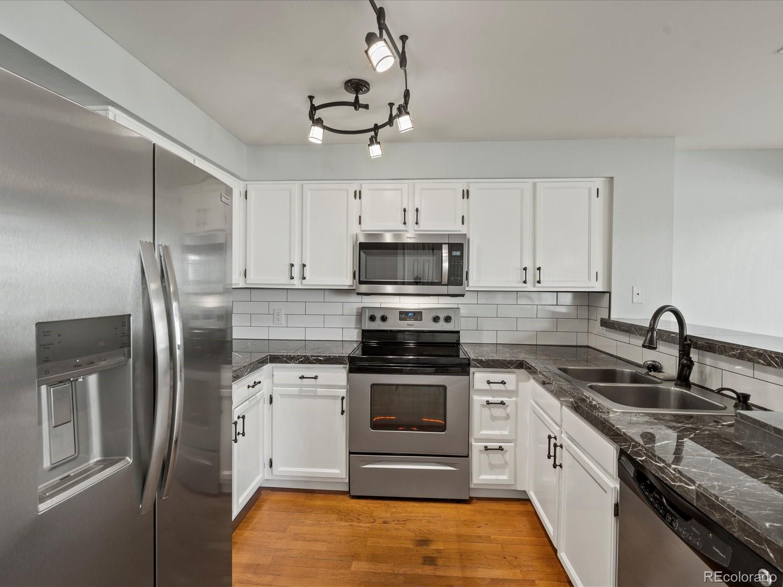 a kitchen with stainless steel appliances granite countertop a sink a stove a refrigerator cabinets and a refrigerator