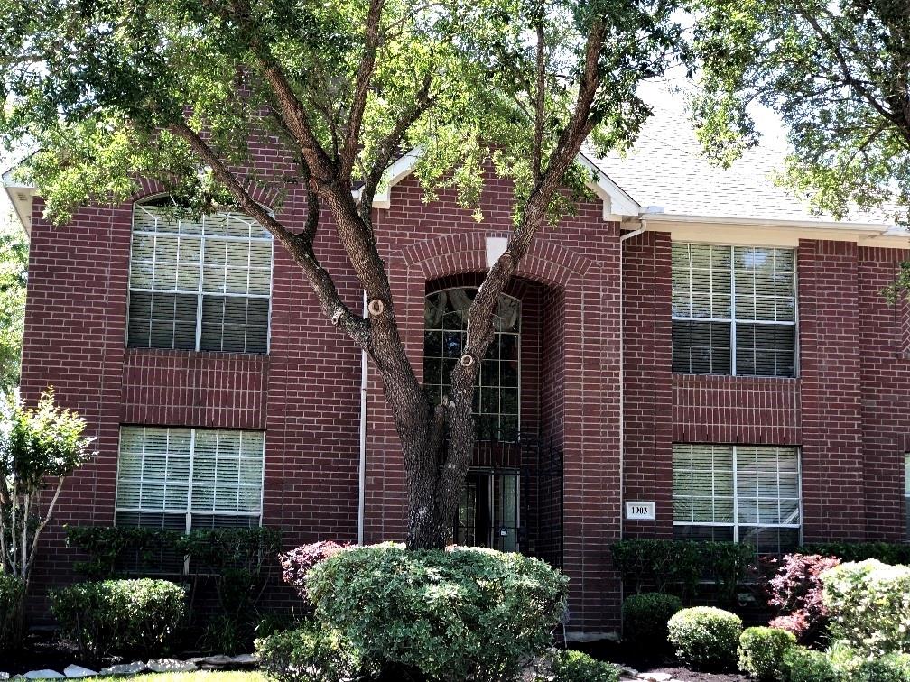 a front view of a house with a tree