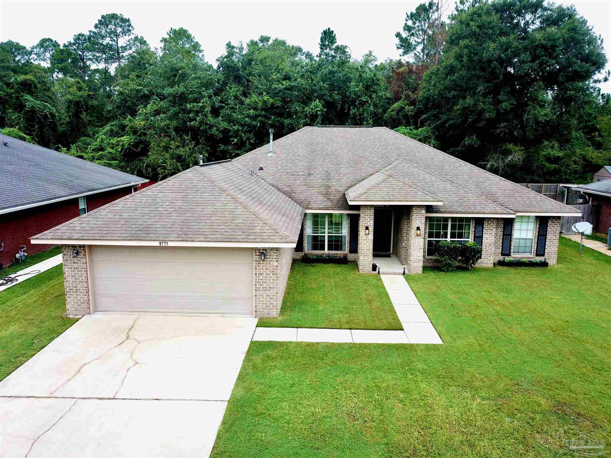 a aerial view of a house next to a big yard with large trees