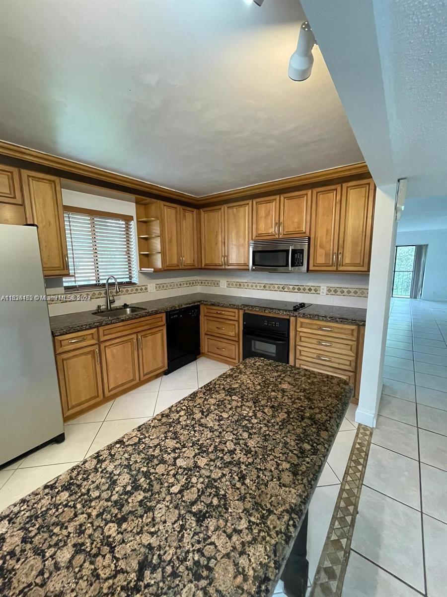 a kitchen with kitchen island granite countertop a stove sink and cabinets