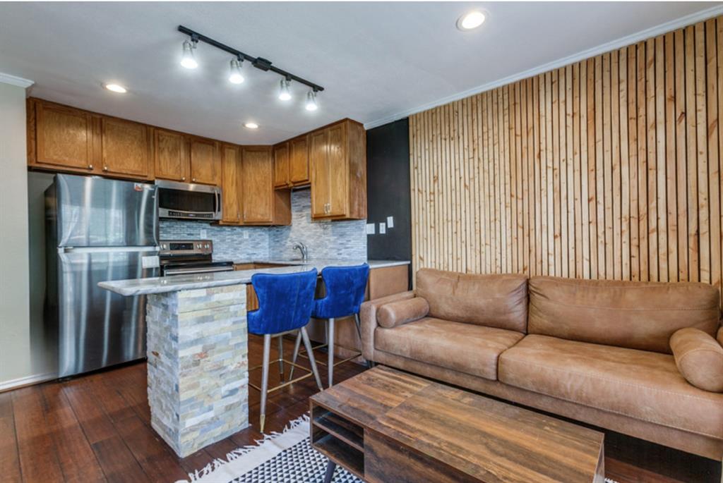 a living room with stainless steel appliances furniture a rug and a kitchen view