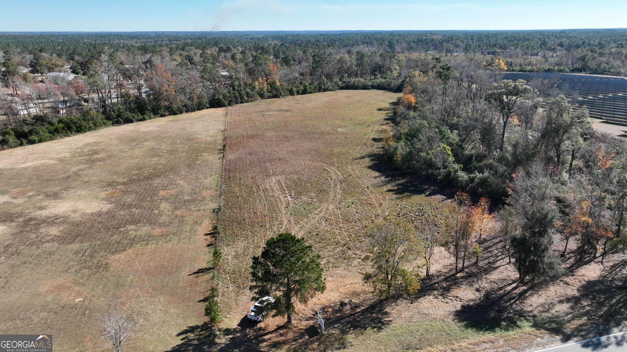 a view of a dry yard with trees in the background