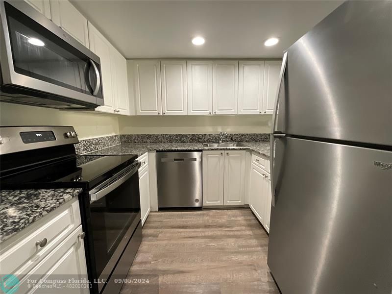 a kitchen with stainless steel appliances granite countertop a stove a refrigerator and a microwave