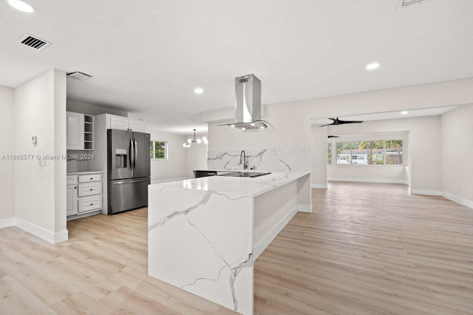 a large white kitchen with cabinets a refrigerator and a sink