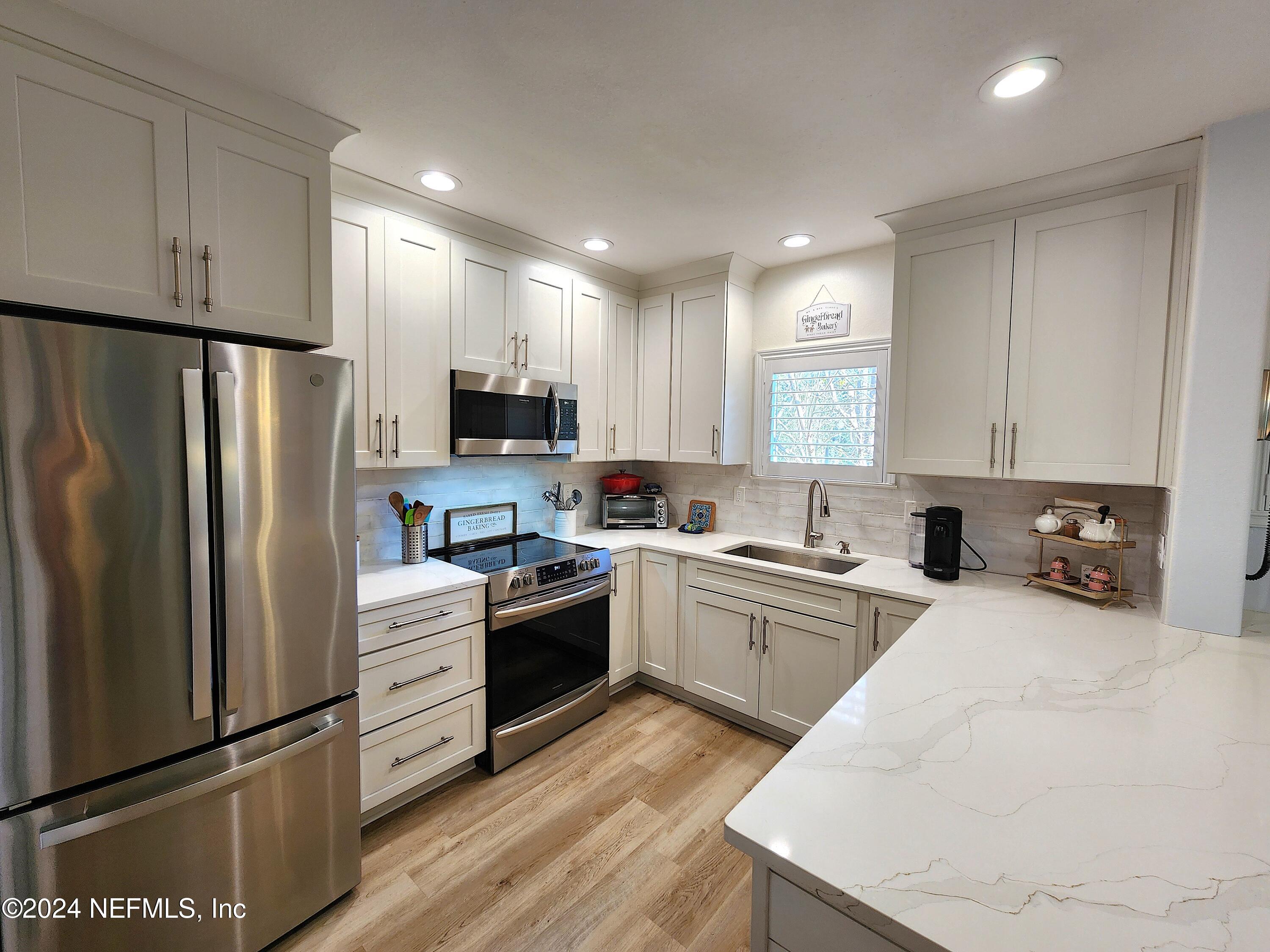 a kitchen with granite countertop a refrigerator stove and sink