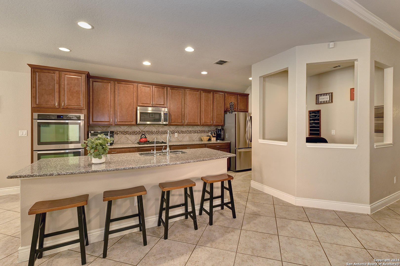 a kitchen with stainless steel appliances granite countertop a stove a sink a microwave a refrigerator and cabinets