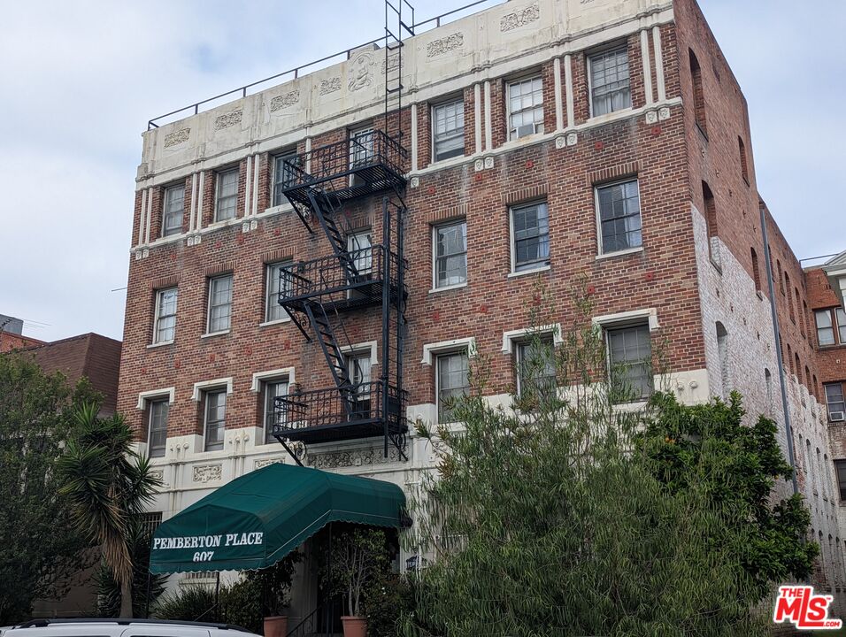 a front view of a building with plants and seating space