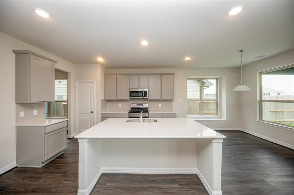 a view of a kitchen with kitchen island a sink dishwasher a stove and a refrigerator with wooden floor