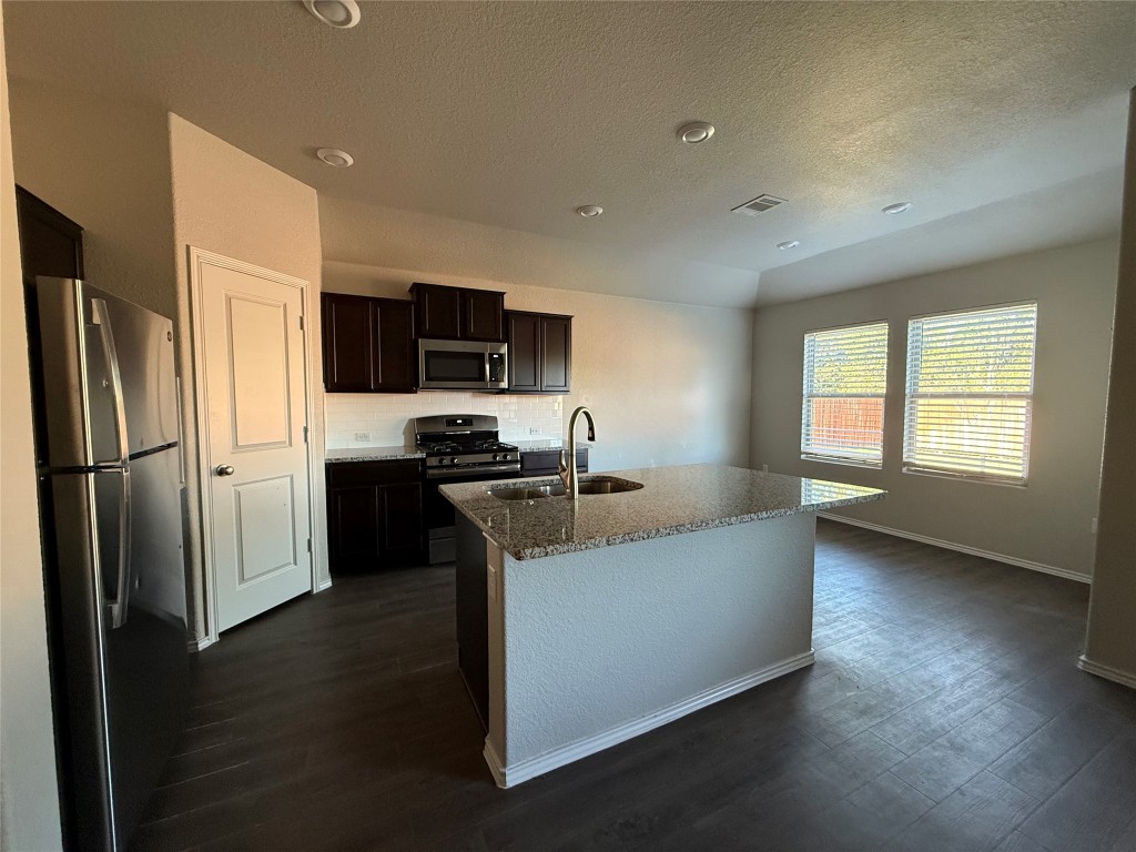 a kitchen with a refrigerator and a stove top oven