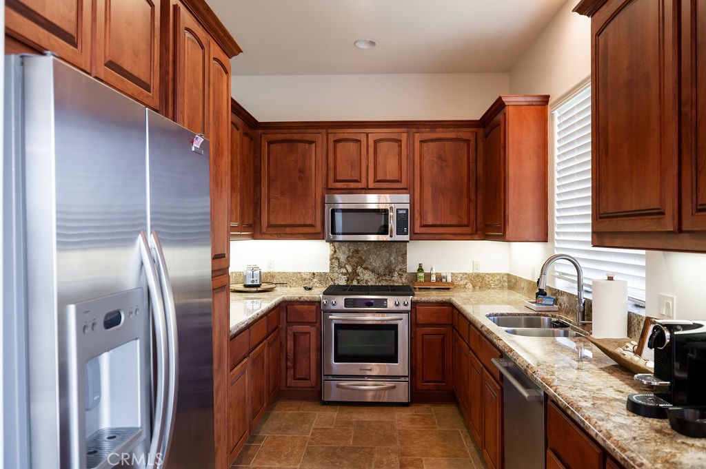 a kitchen with stainless steel appliances granite countertop a stove a sink dishwasher and a refrigerator