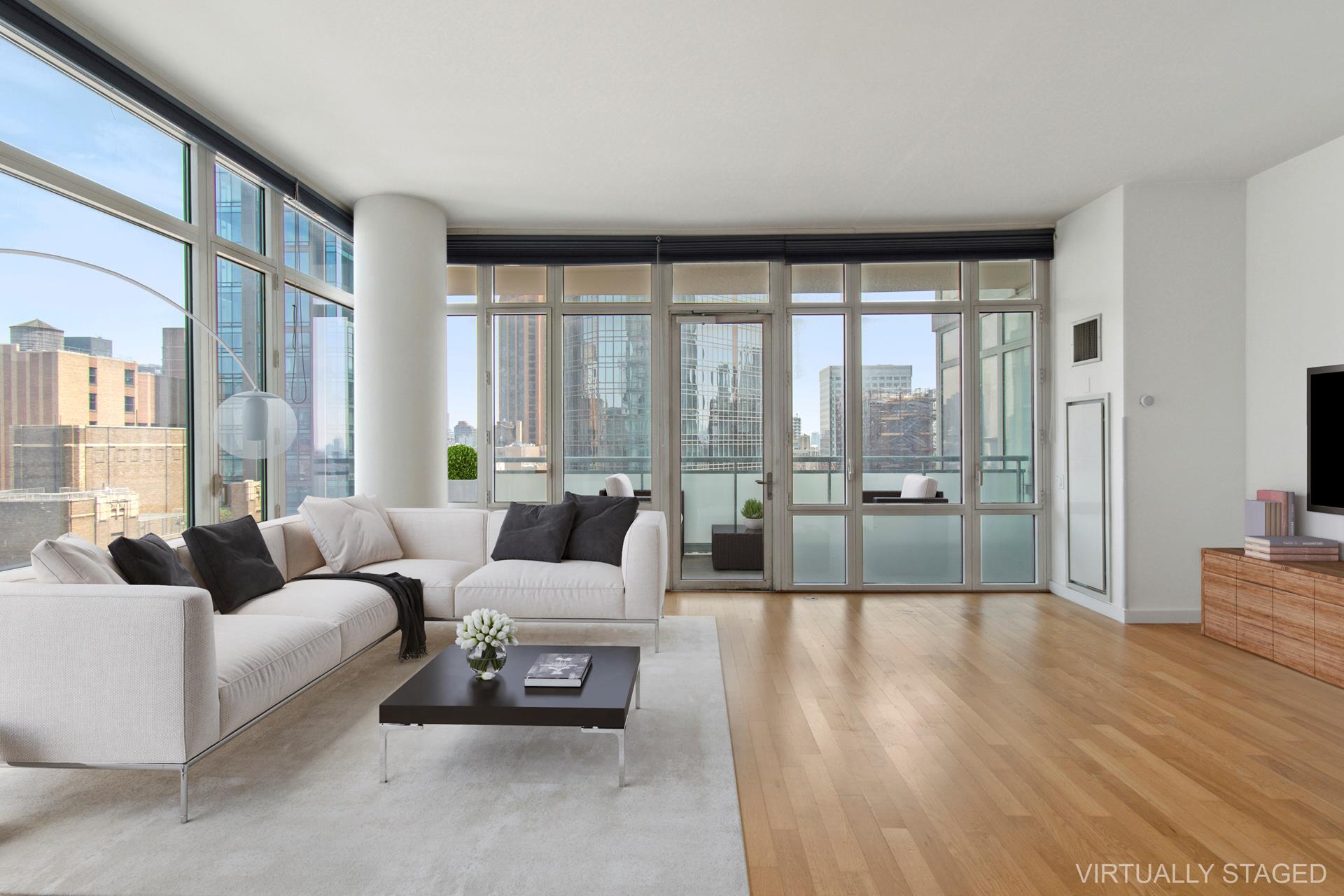 a living room with furniture large windows and wooden floor