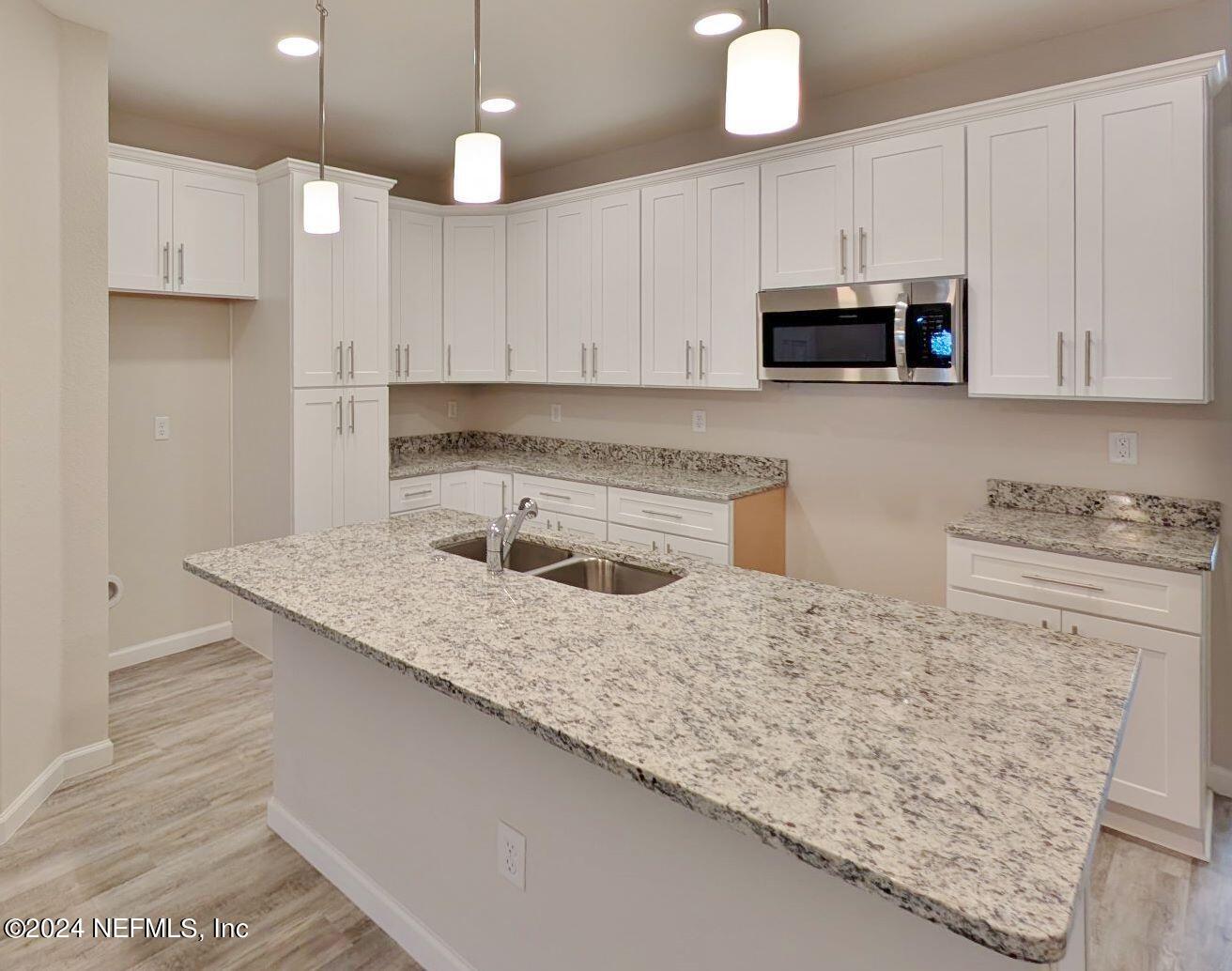 a kitchen with stainless steel appliances granite countertop a sink a stove and a white cabinets