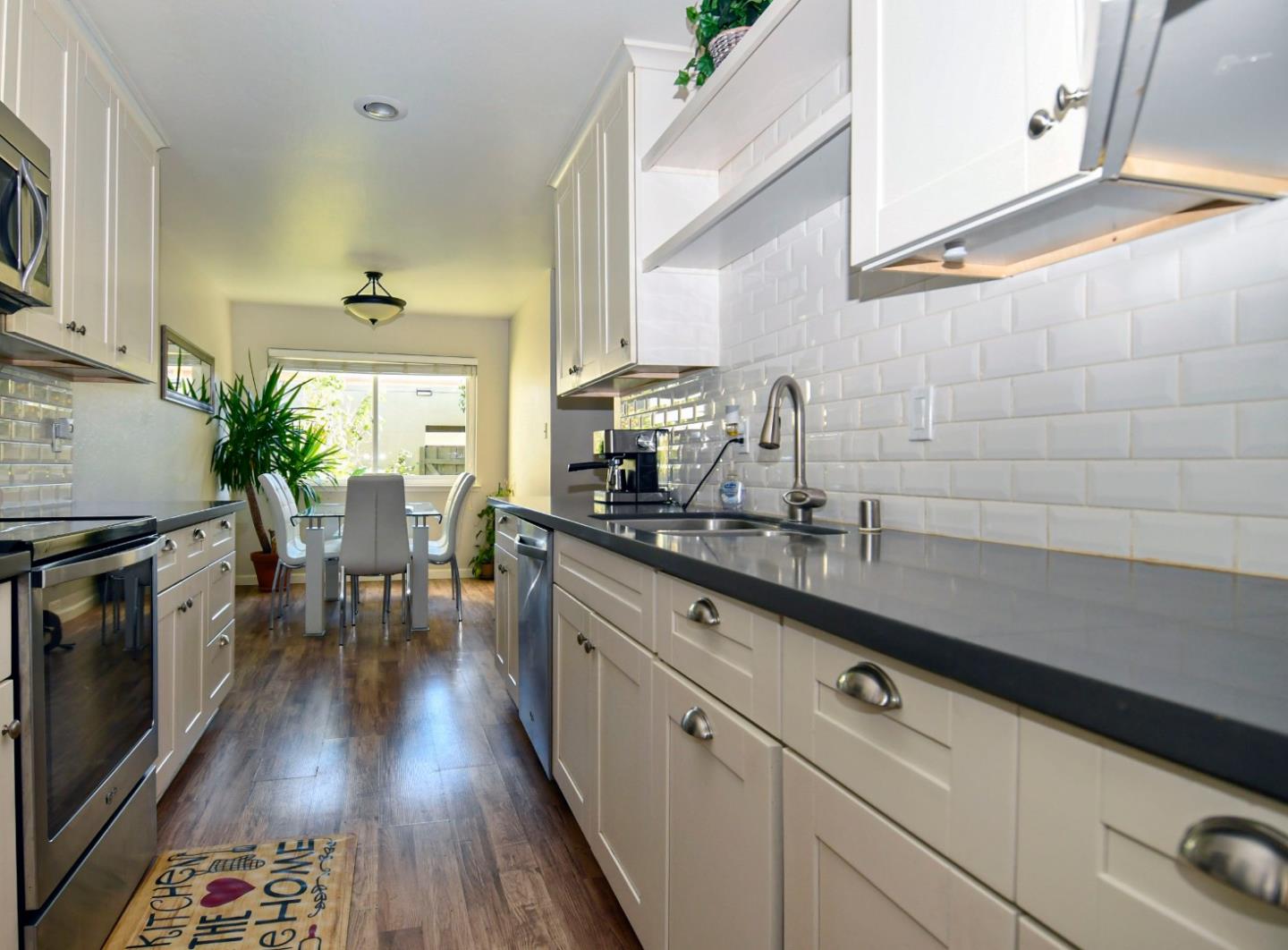 a kitchen with stainless steel appliances white cabinets a sink and wooden floor