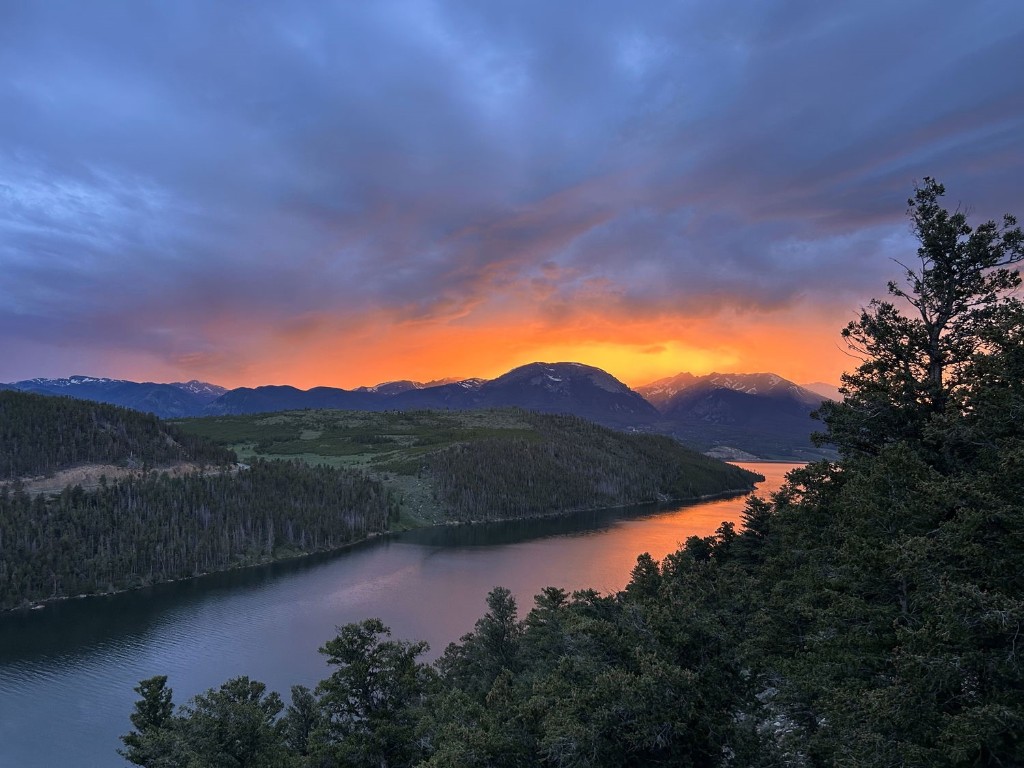 a view of a lake with sunset in background