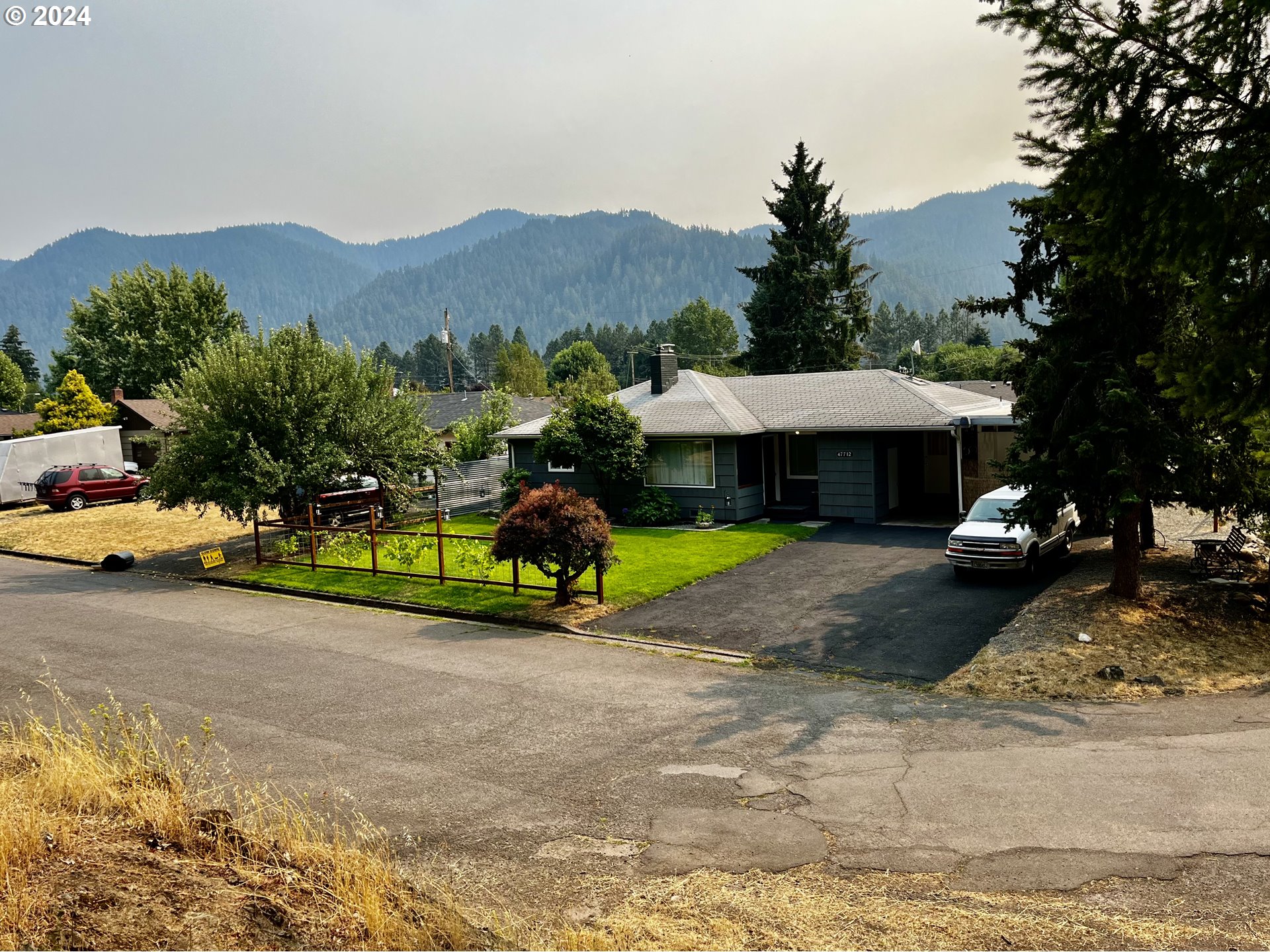 a front view of a house with a garden and mountain view