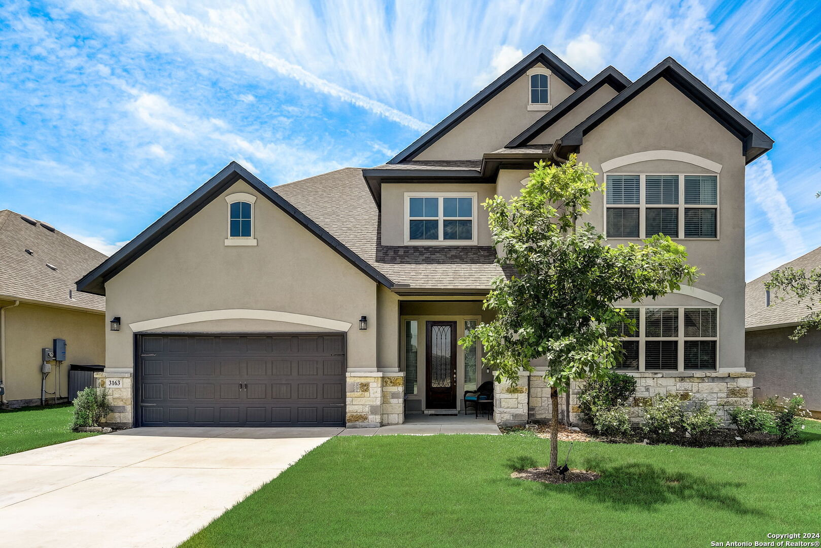 a front view of a house with a yard and trees