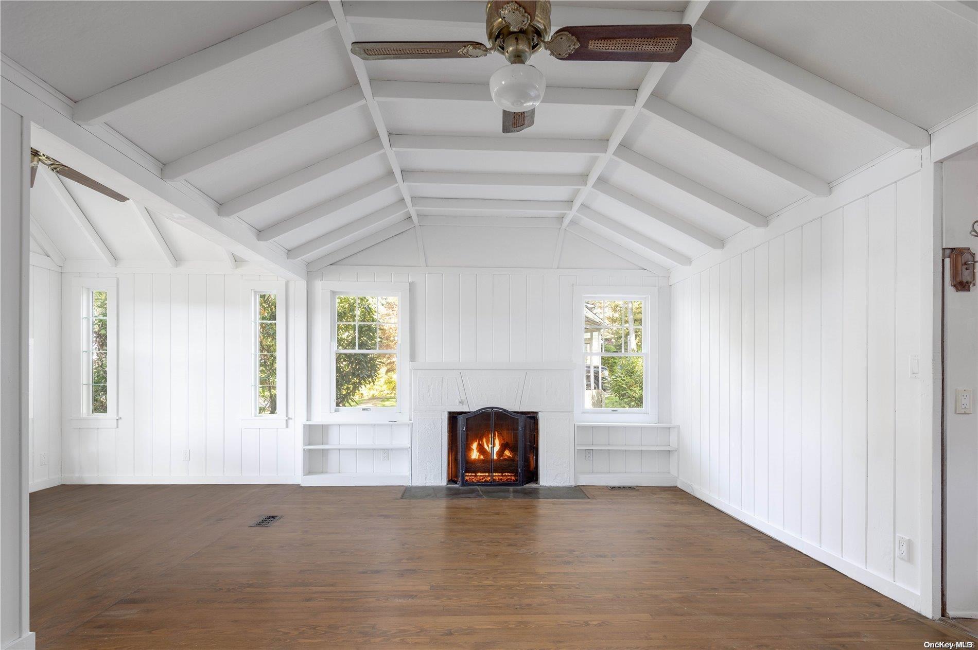 an empty room with windows and fireplace