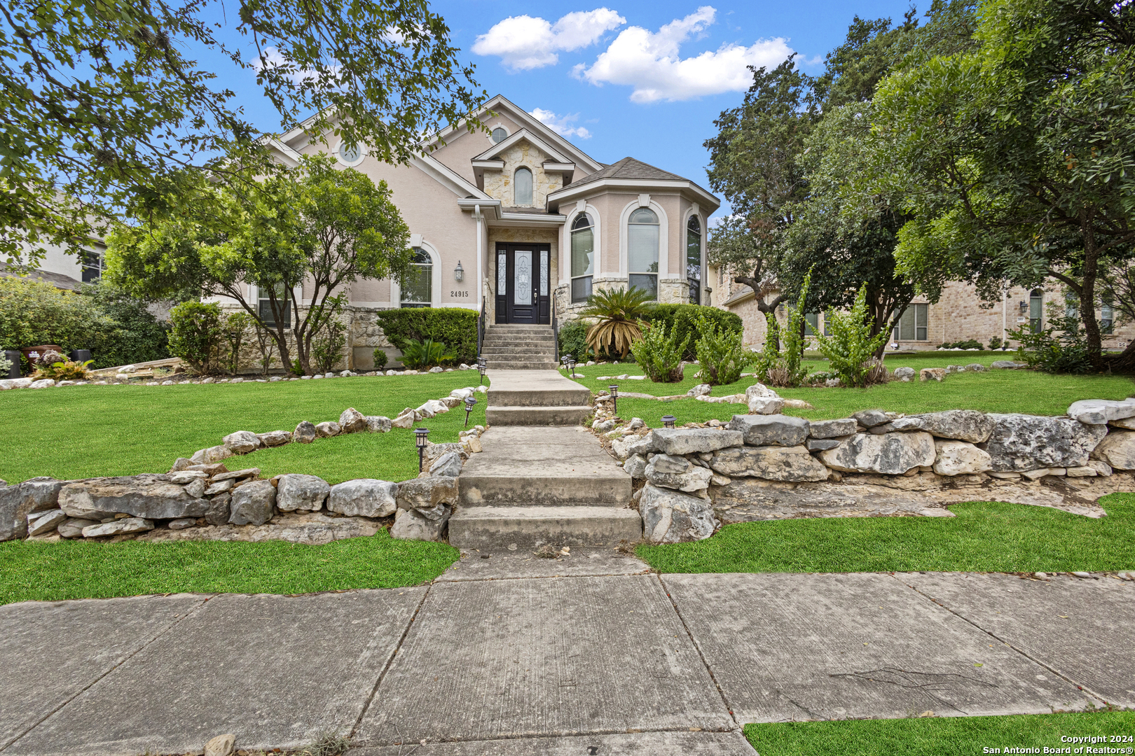 a front view of a house with a yard and potted plants