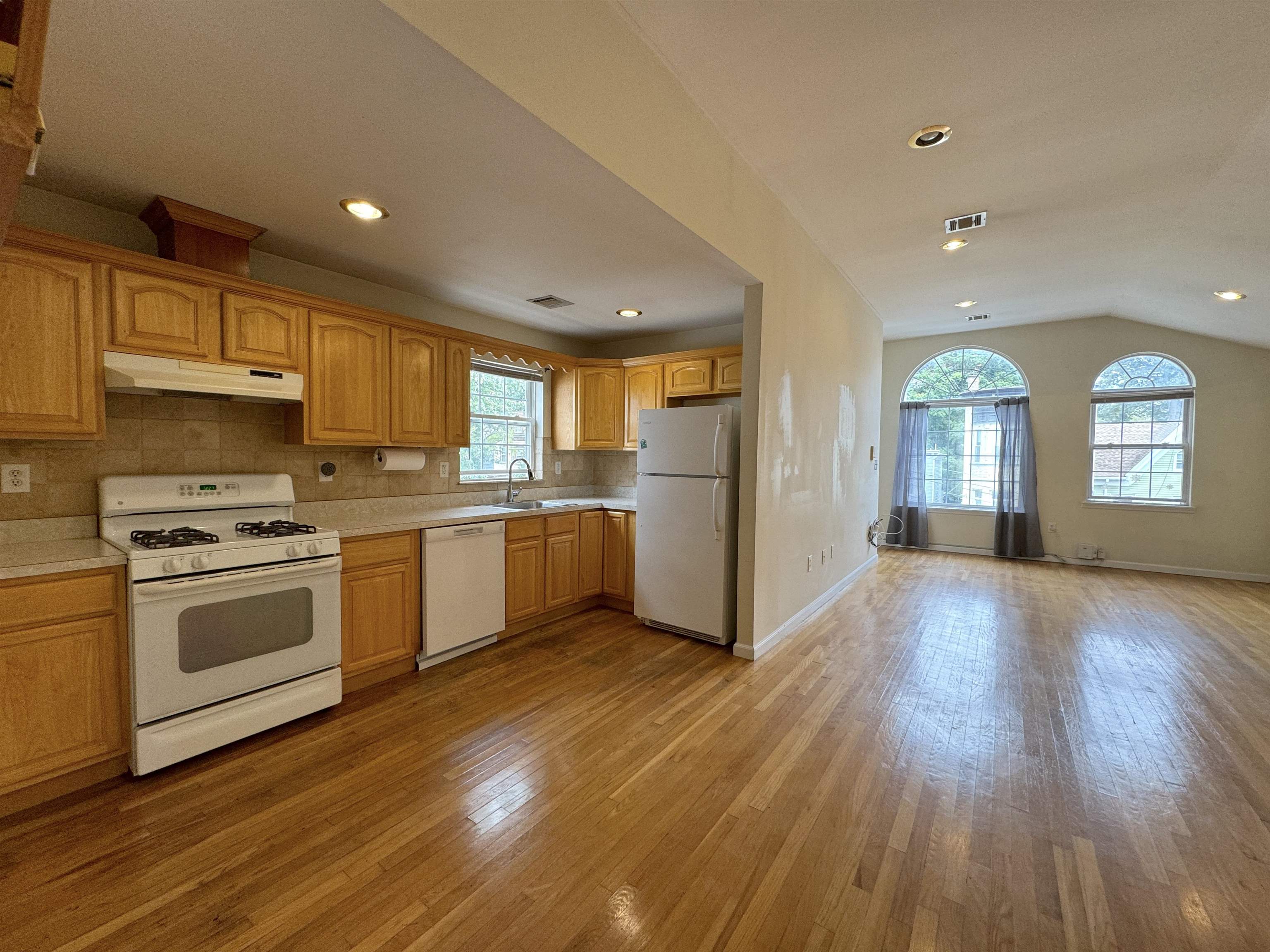 a kitchen with wooden floors and white stainless steel appliances