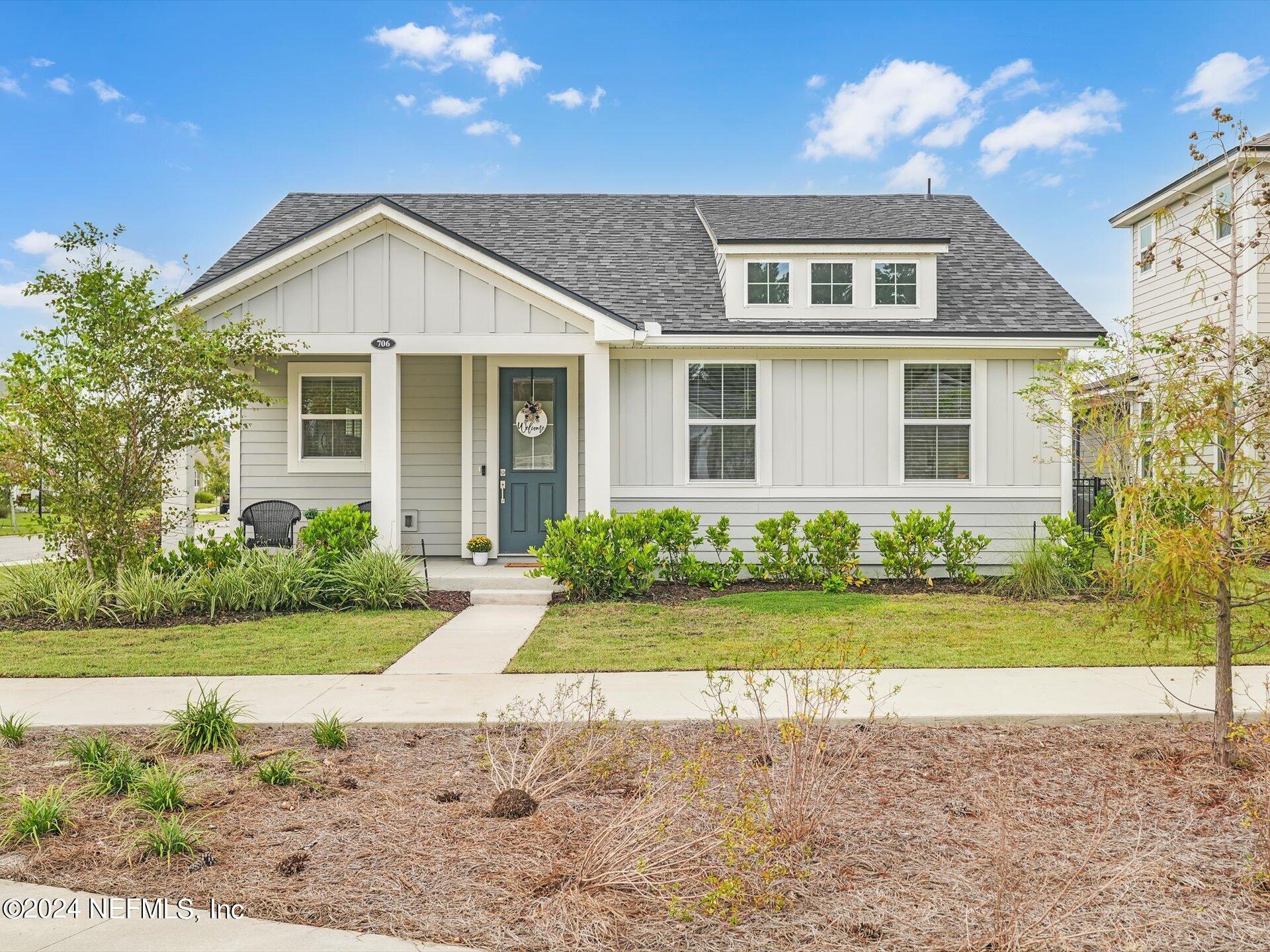 a front view of a house with a yard and potted plants