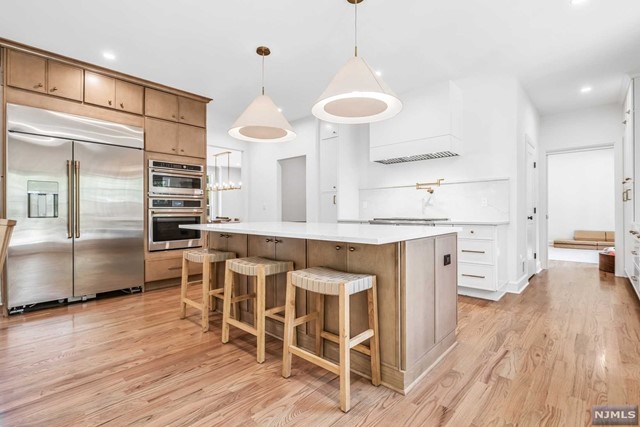 a kitchen with stainless steel appliances a dining table chairs and wooden floor