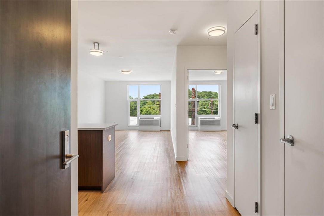 Hall with an AC wall unit and light wood-type flooring