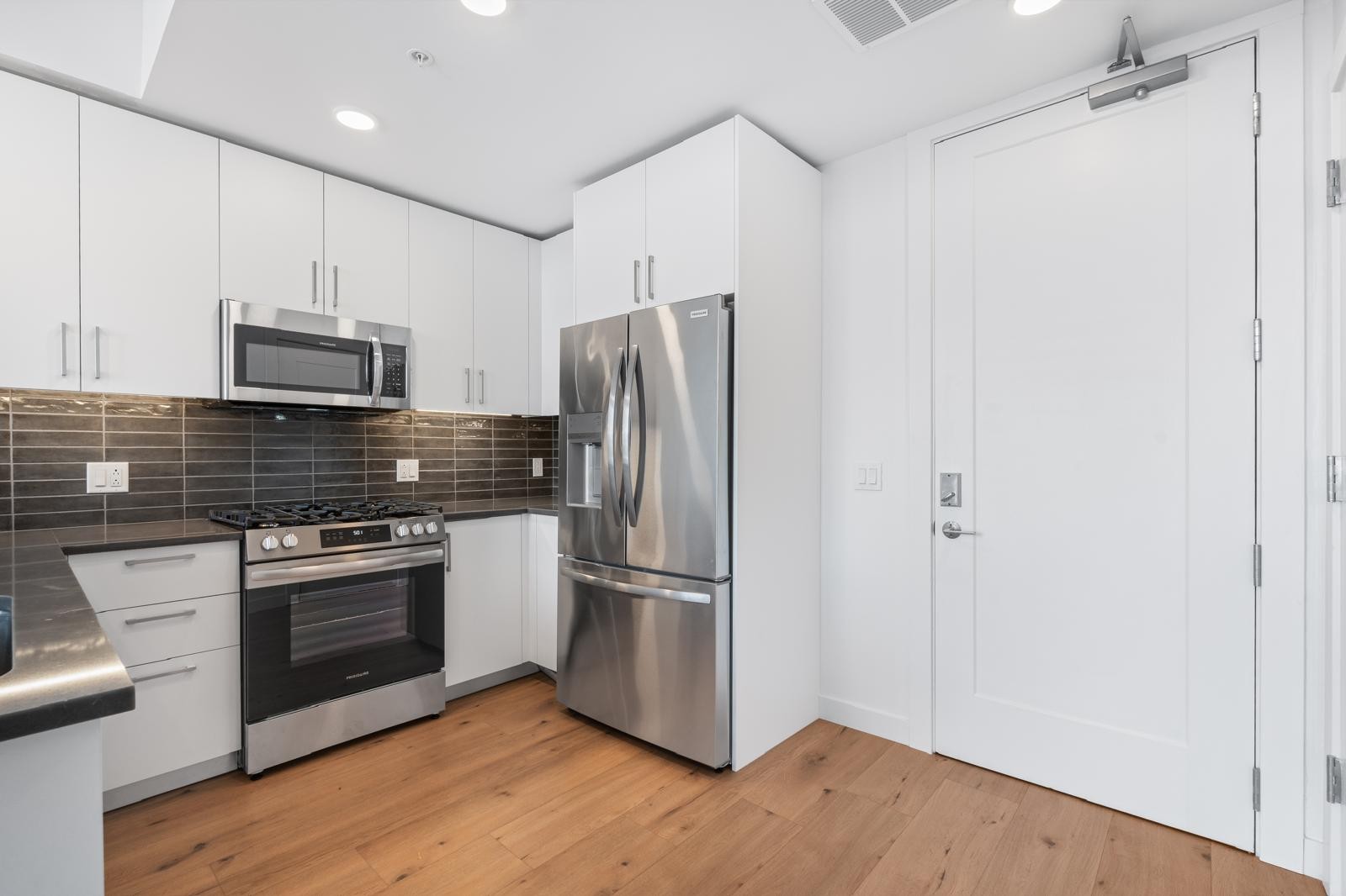 a kitchen with granite countertop a refrigerator stove and microwave