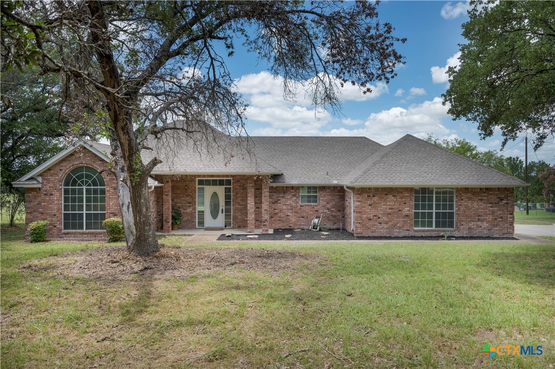 a front view of house with yard and trees in the background