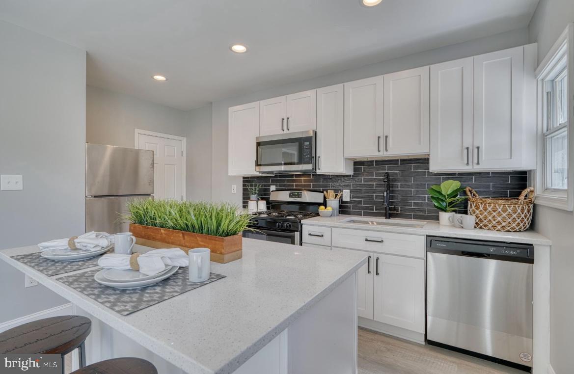 a kitchen with stainless steel appliances kitchen island granite countertop a sink a stove a dining table and chairs