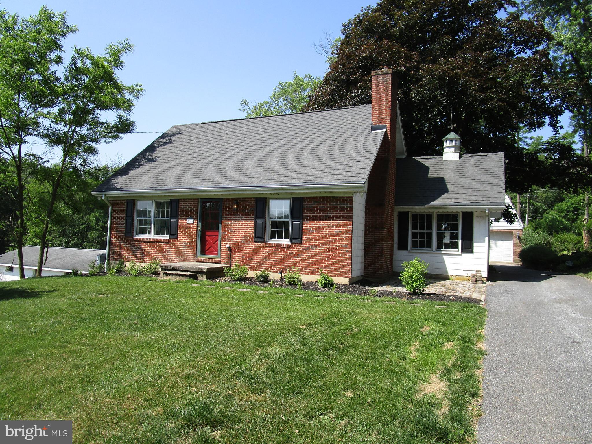 a front view of a house with a garden and trees