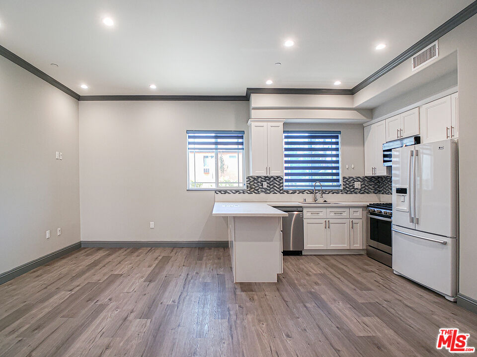 a kitchen with a refrigerator and white cabinets