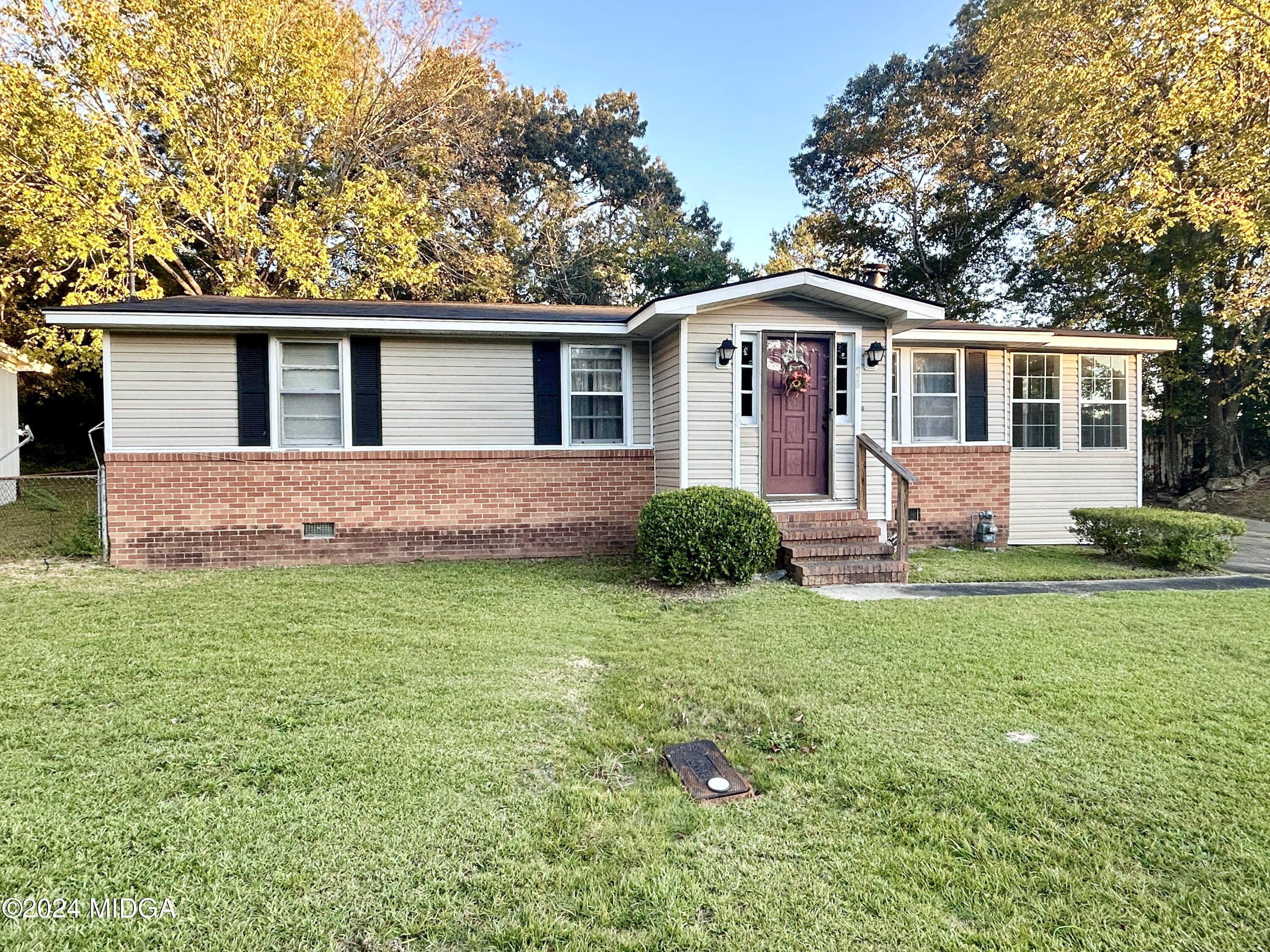 a front view of house with yard and trees in the background