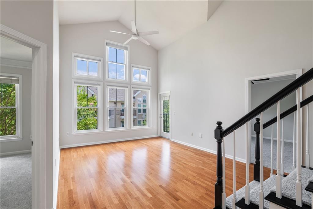 a view of an empty room with wooden floor and fan