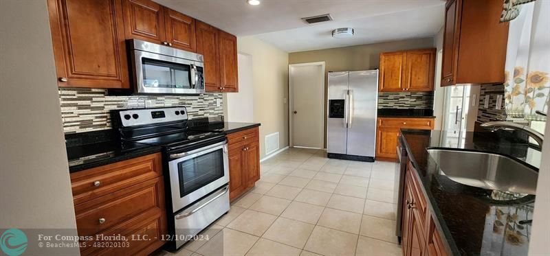 a kitchen with stainless steel appliances granite countertop a stove microwave and sink