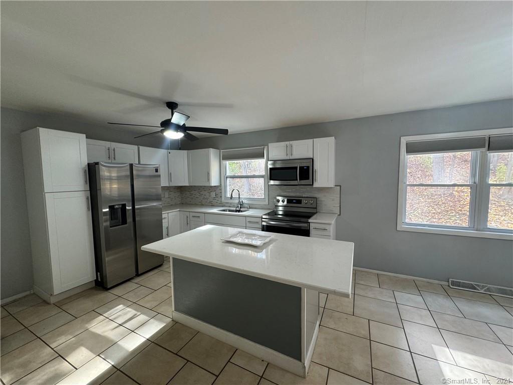 a kitchen with a sink a counter top space stainless steel appliances and cabinets