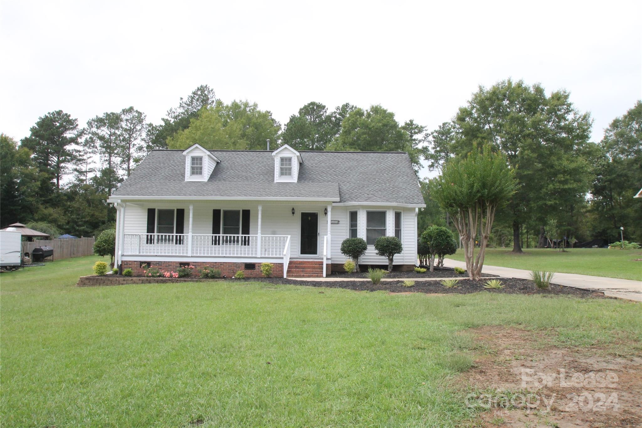 a front view of a house with garden and trees