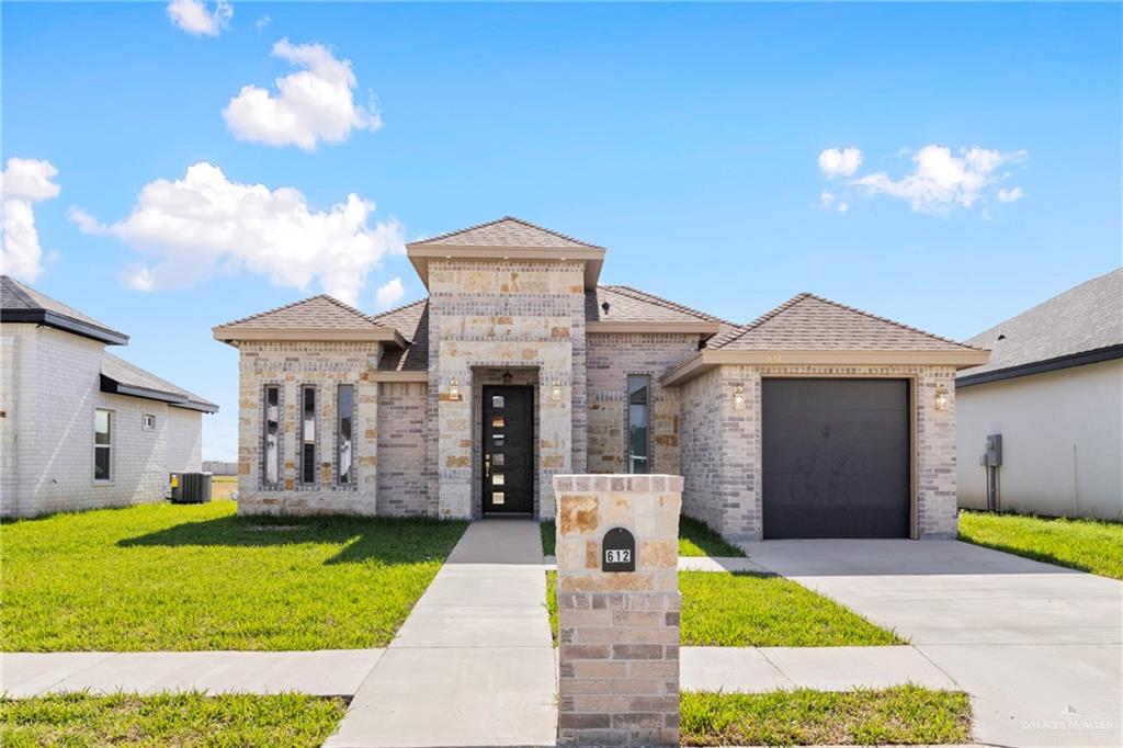 View of front of property with a garage, a front yard, and central AC