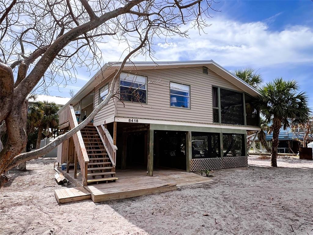 a front view of a house with stairs yard and tree s