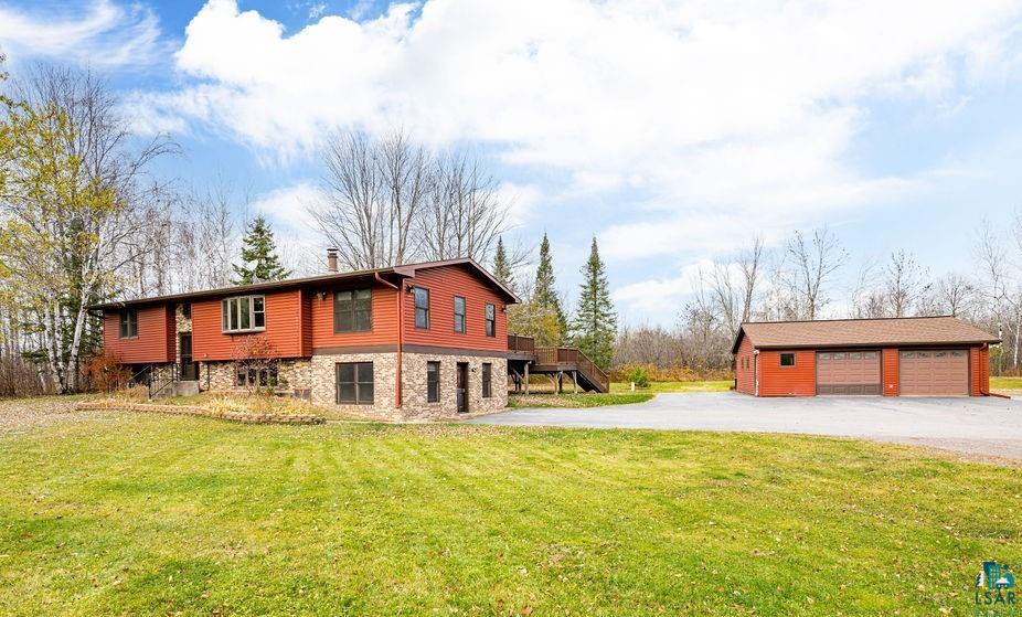 View of property exterior featuring a garage, a lawn, and an outdoor structure