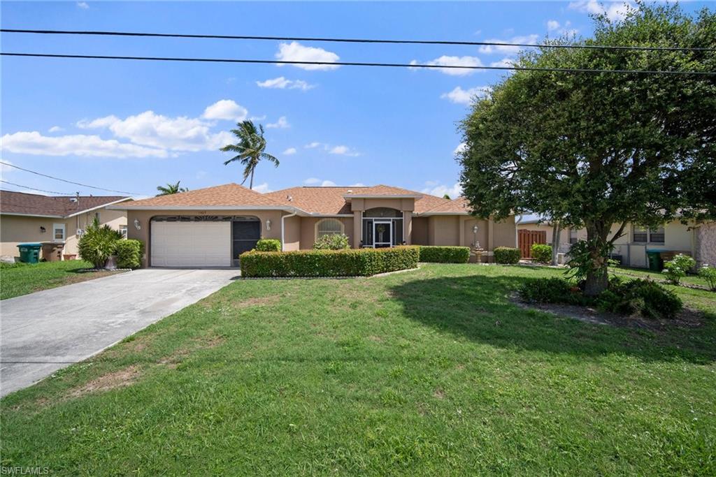 Ranch-style home featuring a garage and a front lawn